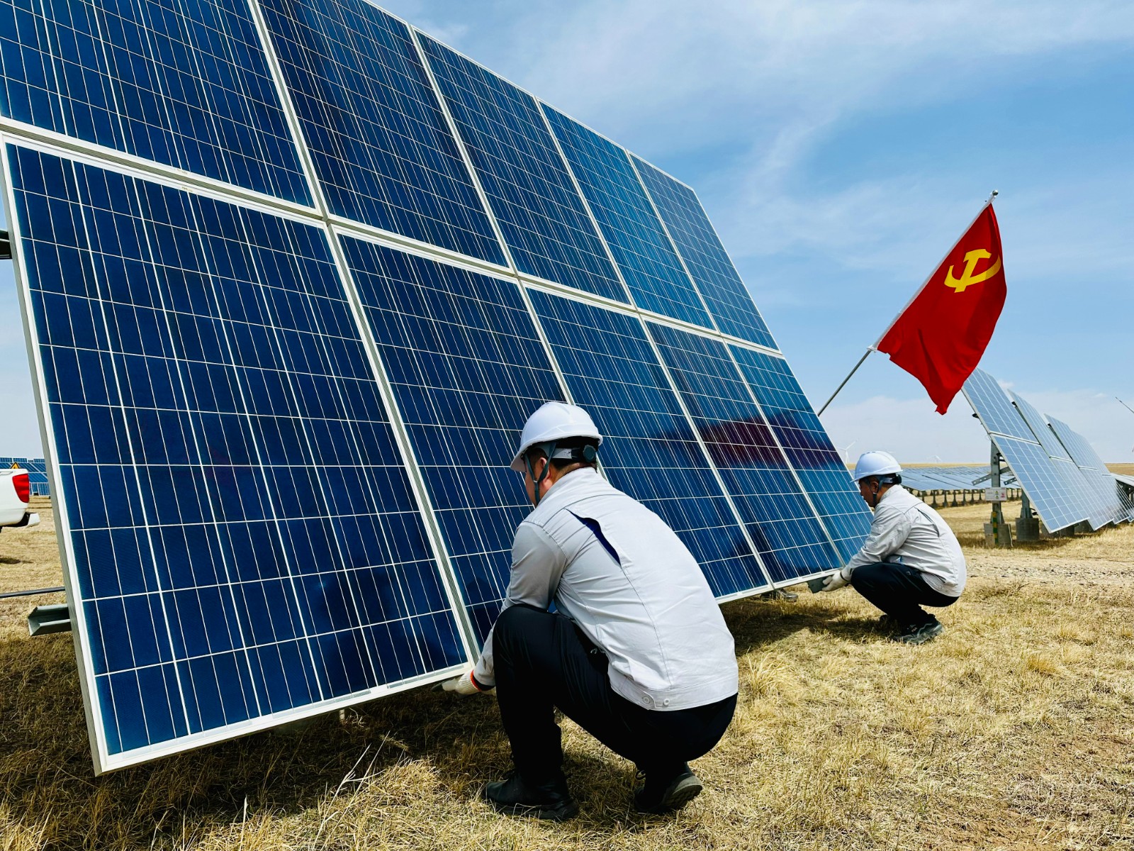 圖為機(jī)關(guān)職工與駐場(chǎng)職工抬扶光伏板